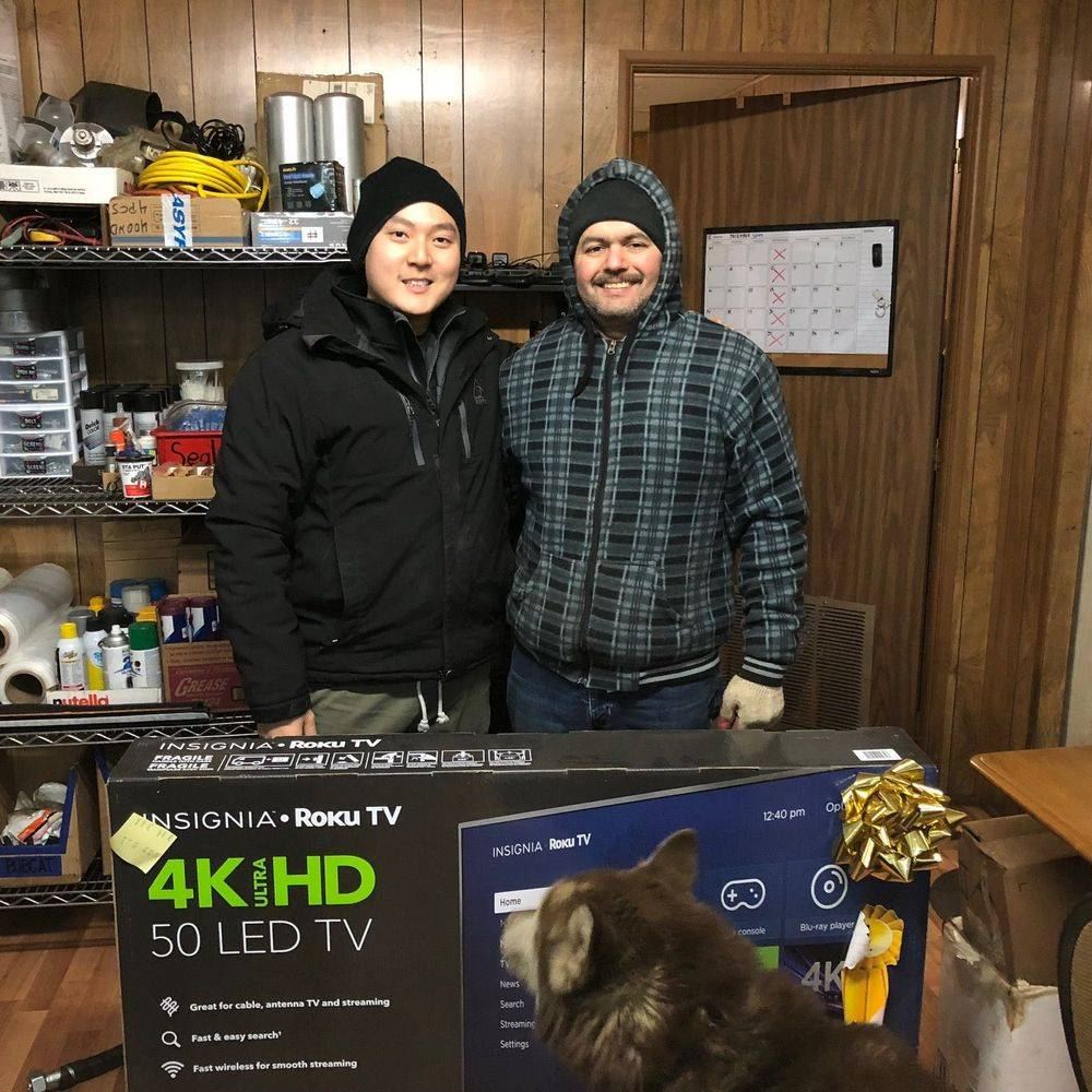Two men behind a counter with a boxed 50-inch television.